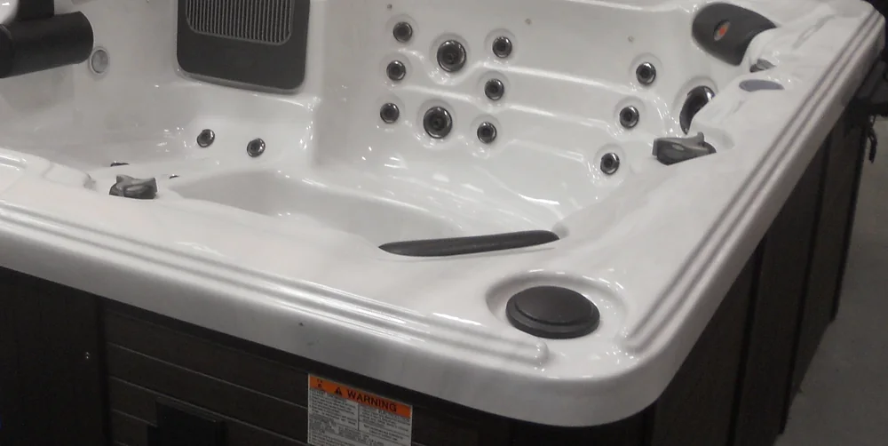 Photo of a white acrylic portable hot tub shell with molded seats, jets and a filter lid