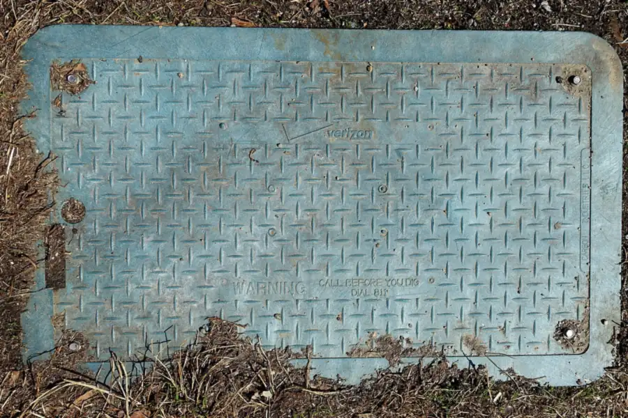 Photo of a utility box cover set in a lawn edge, stamped with a warning to call 811 before you dig
