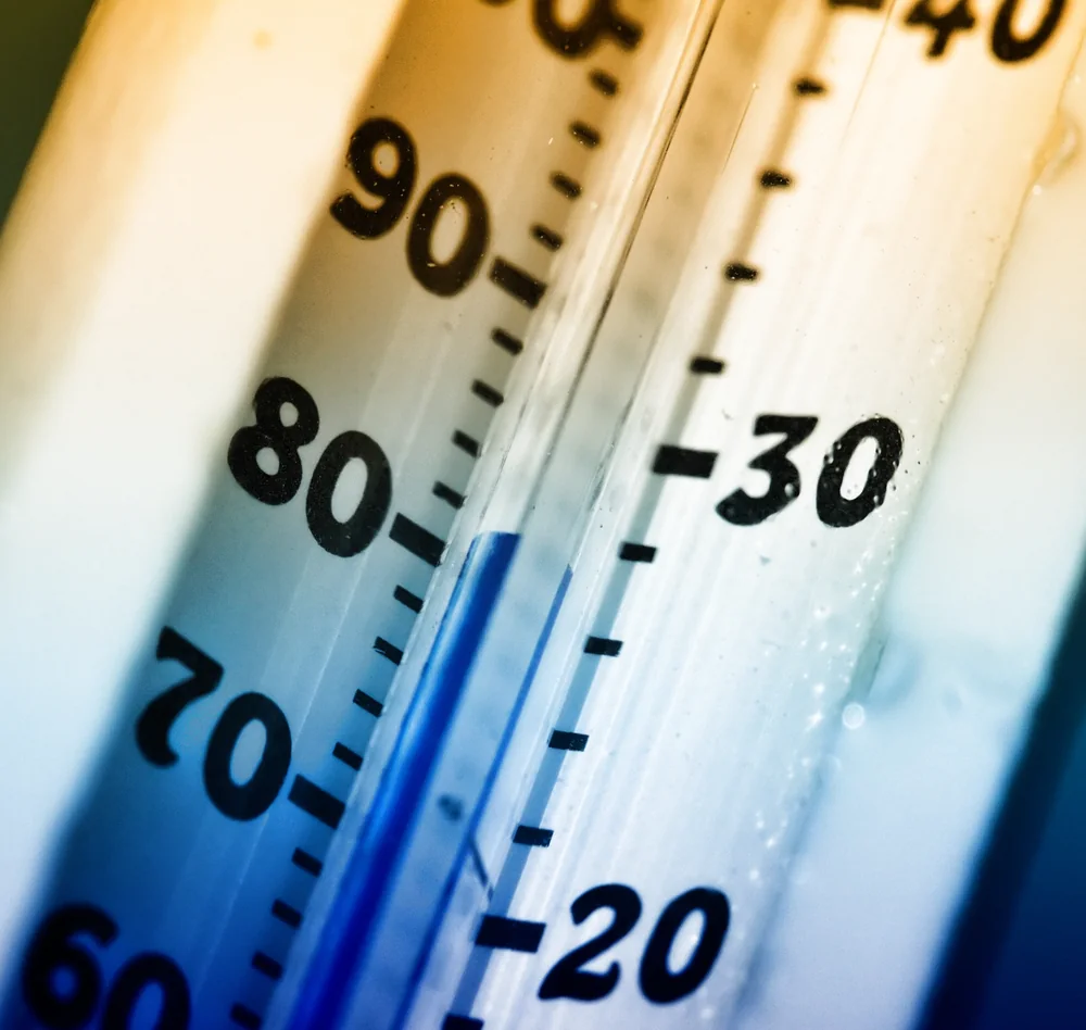 Photo of a pool thermometer close up, its blue liquid column reading close to 80°F on the Fahrenheit scale