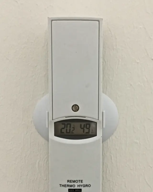Photo of a white wall thermo-hygrometer whose display reads 20.2°C and 49% relative humidity