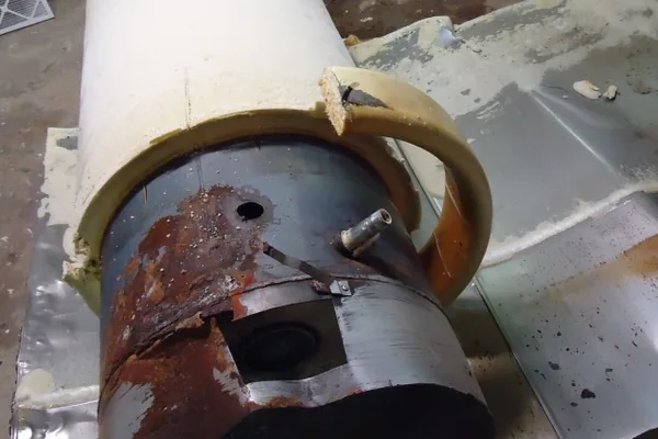 Photo of a retired water heater tank with its foam insulation and white outer jacket partly cut away